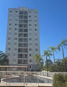 a tall building with palm trees in front of it at Apartamento no portal dos ipes cajamar in Cajamar