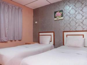 two beds sitting next to each other in a room at Hotel Tiara in Cukai