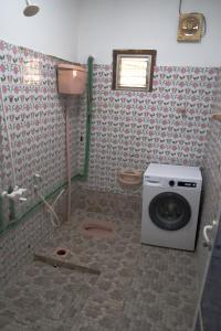 a bathroom with a washing machine and a toilet at Blue Wave Home in Al Bustān