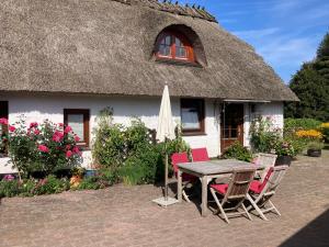 a table and chairs in front of a thatched house at Ferienwohnung Piesch in Glücksburg