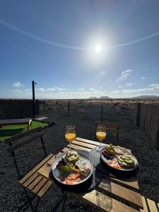 two plates of food on a table with glasses of wine at Villa Miraki Fuerteventura Surf Relax in La Oliva