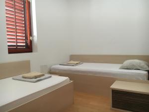 two twin beds in a room with a window at Apartments Jakišnica in Jakišnica
