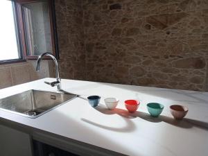 four bowls sitting on a counter next to a sink at Casa das Cazolas in Oia +32 photos