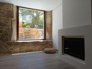 a living room with a fireplace and a window at Casa das Cazolas in Oia