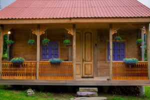 a wooden house with purple windows and potted plants at Forest Dream ტყის სიზმარი in Tsʼageri