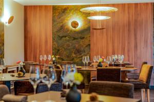 a restaurant with tables and chairs and a painting on the wall at Demeures & Châteaux Auberge de la Tour - Hôtel & Restaurants - Marcolès Auvergne in Marcolès