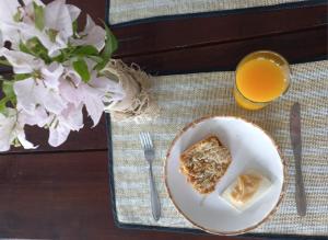 a plate with a piece of cake and a glass of orange juice at Pousada Manacá in São José do Rio Pardo