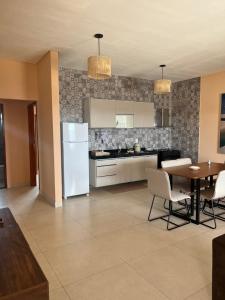 a kitchen with a white refrigerator and a table at Casa Lago Santo Amaro in Queimada