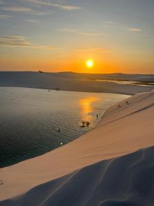 a sunset over the ocean on a beach with a sand dune at Casa Lago Santo Amaro in Queimada