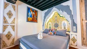 una camera da letto con un letto e un dipinto sul muro di PALACIO AL ANDALUS a Chefchaouen Altre 37 foto