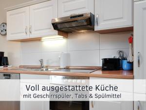 une cuisine avec des armoires blanches et un four à plaques de cuisson dans l'établissement Lotsenglück Fehmarn, Nähe Hafen Burgstaaken, perfekt für Familien & Paare, à Burg