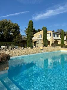 a large blue swimming pool in front of a building at Le Bastidon des Mésanges in Gordes