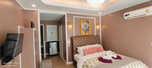 ein Schlafzimmer mit einem Bett mit rosa Kissen und einem Fernseher in der Unterkunft Clear View Resort in Ko Tao