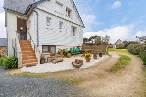 une maison blanche avec une table et quelques plantes en pot dans l'établissement Appartement douillet et reposant- Proche Plages et commerces, à Trégastel