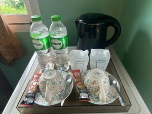 a tray with two bottles of water and plates and water pitchers at Dhammachart RiverView in Samut Songkhram