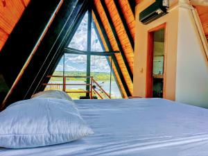 a bed in a room with a large window at Chalé Recanto - ofurô, banheira, vista, cachoeira e lago in Alexânia