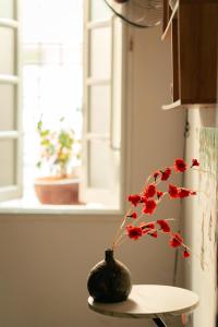 a vase with red flowers sitting on a table at Morri Homestay - Quán Thánh in Hanoi