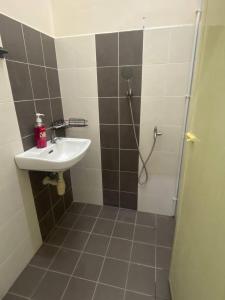 ein Bad mit einem Waschbecken und einer Dusche mit einer Dusche in der Unterkunft Homestay Rumoh Mok in Jitra