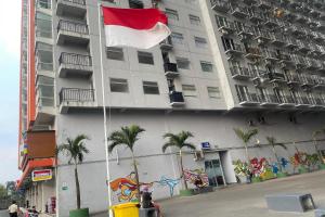 a flag flying in front of a building with palm trees at Hotel O Grand Asia Afrika Apartment By Qr Property in Bandung