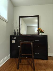 a black dresser with a mirror and a wooden stool at Cozy Basement rooms 2 bedroom 2 queen beds home stay in halifax Nova Scotia in Timberlea