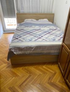 a bed in a bedroom with a wooden floor at Welcome to my happy place in the center of Gjakova in Gjakove