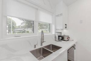 eine weiße Küche mit Spüle und Fenster in der Unterkunft South Oakville Bliss Haven in Oakville + 119 Fotos