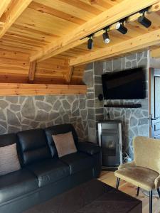 a living room with a black leather couch and a fireplace at Mala Vila Sofija in Mojkovac