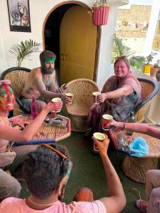 a group of people sitting around a table with drinks at Manavi Hostel Near by Mathura Railway Station in Mathura