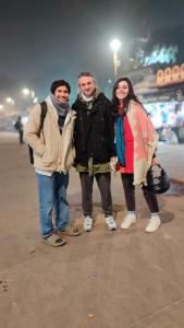three people standing next to each other on a street at Manavi Hostel Near by Mathura Railway Station in Mathura