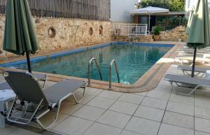 a swimming pool with chairs and an umbrella at Kiwi Kastle in Nea Fokea