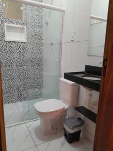 a bathroom with a toilet and a glass shower at Pousada Flor da Barra in Maragogi