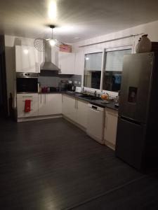 a kitchen with white cabinets and a black refrigerator at Ma gimeloise in Gimel +6 photos