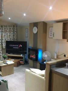 a living room with a flat screen tv and a couch at Luxury static caravan, 6 berth, Marine Holiday Park, Rhyl, Wales in Rhyl