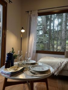 a table with glasses and plates on it in a room with a window at Suite del muelle in San Carlos de Bariloche