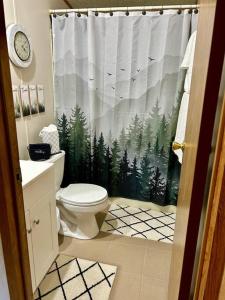 a bathroom with a toilet and a shower curtain with trees at Grassy Meadow Getaway - HOT TUB! in Mount Nebo +33 photos