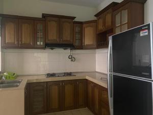 a kitchen with wooden cabinets and a black refrigerator at Bangi in Kajang