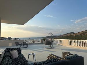 eine Terrasse mit einem Sofa und Stühlen auf dem Balkon in der Unterkunft Vila Chelsea in Ksamil