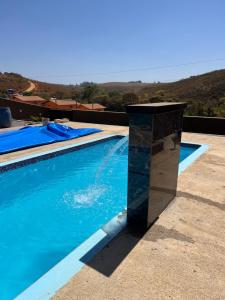 Una piscina con un pilar de piedra al lado. en Chácara do Pepê, en São Roque de Minas