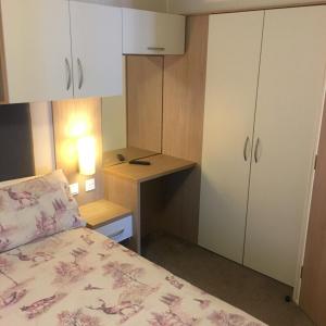 a small bedroom with a bed and a desk at Luxury static caravan, 6 berth, Marine Holiday Park, Rhyl, Wales in Rhyl +56 photos