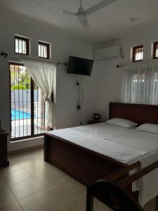 1 dormitorio con cama, TV y piscina en Angila Villa Negombo, en Negombo