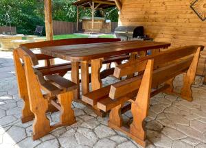 a wooden table and benches in front of a cabin at Blanka Vendégház in Erdőbénye