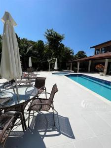 a table and chairs with an umbrella next to a pool at Casa Praia Guaratuba - Bertioga in Bertioga