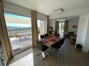 Un comedor con mesa y sillas y una gran ventana. en Villa Leonardo, en Tribunj