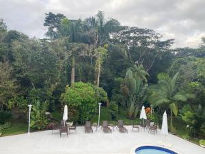a patio with chairs and umbrellas and a pool at Casa Praia Guaratuba - Bertioga in Bertioga +35 photos