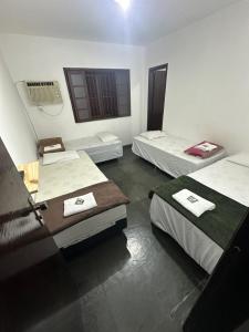 a room with three beds and a window at Pousada e Restaurante Dona Lu in Itaperuna