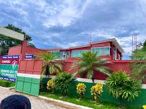 ein rotes Gebäude mit Palmen davor in der Unterkunft Pousada Recanto do Guerreiro Tricolor in Duque de Caxias