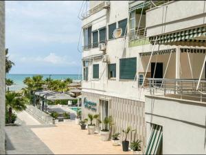 an apartment building with potted plants on a sidewalk next to the ocean at Apartments Qerret Golem beachfront in (( Stan i Ri ))