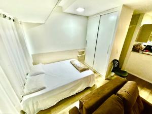 een slaapkamer met een bed, een bank en een spiegel bij Flat Boa Viagem luxo in Recife +30 foto's