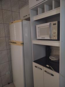 a small kitchen with a refrigerator and a microwave at AP 50 Metros do Mar in Mongaguá