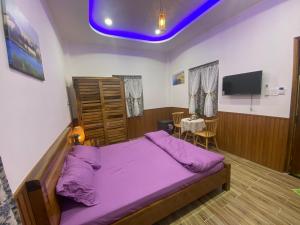 a bedroom with a purple bed and a tv at Sea-Breeze Homestay in Phan Thiet